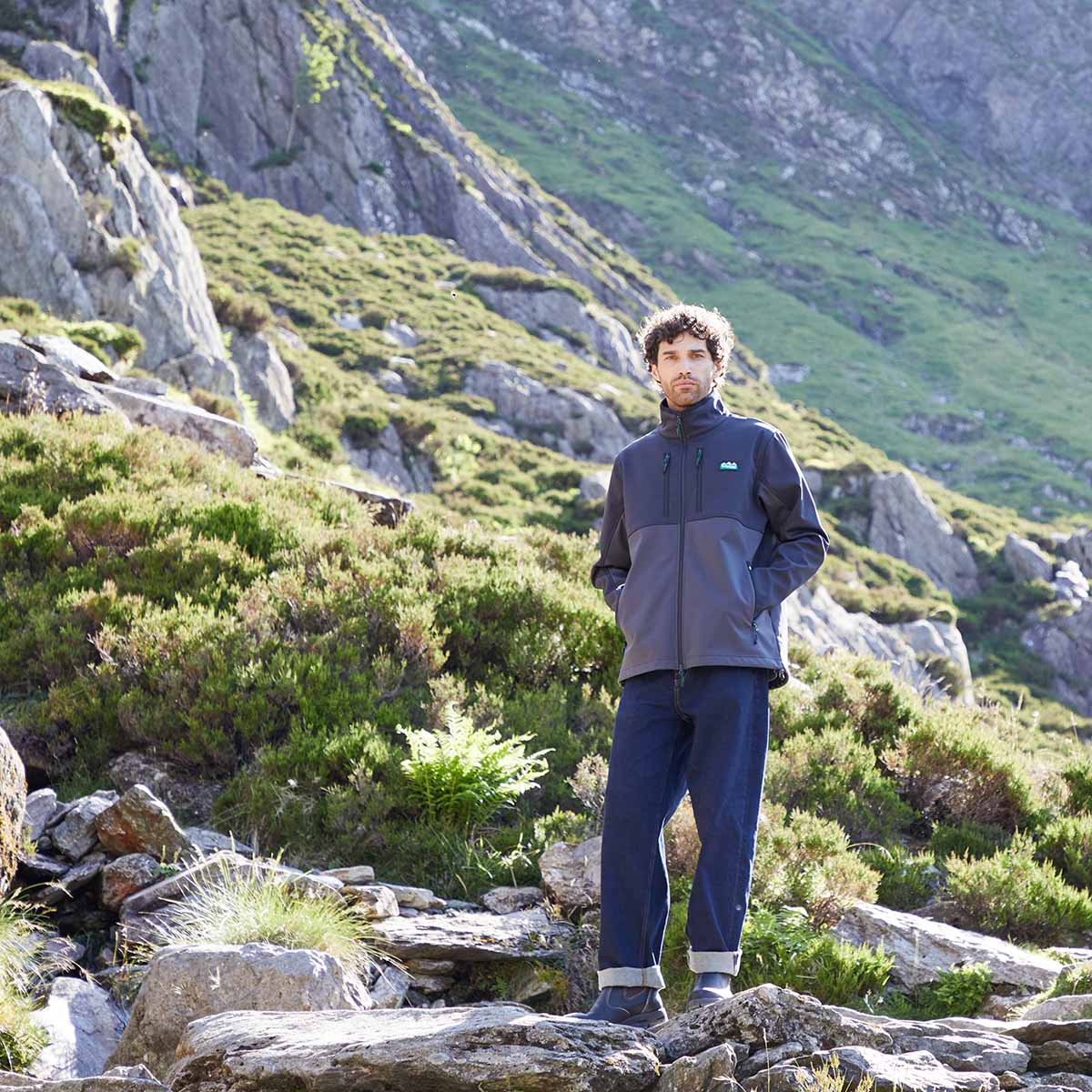 Man standing on a rocky mountain path wearing black windproof fleece.