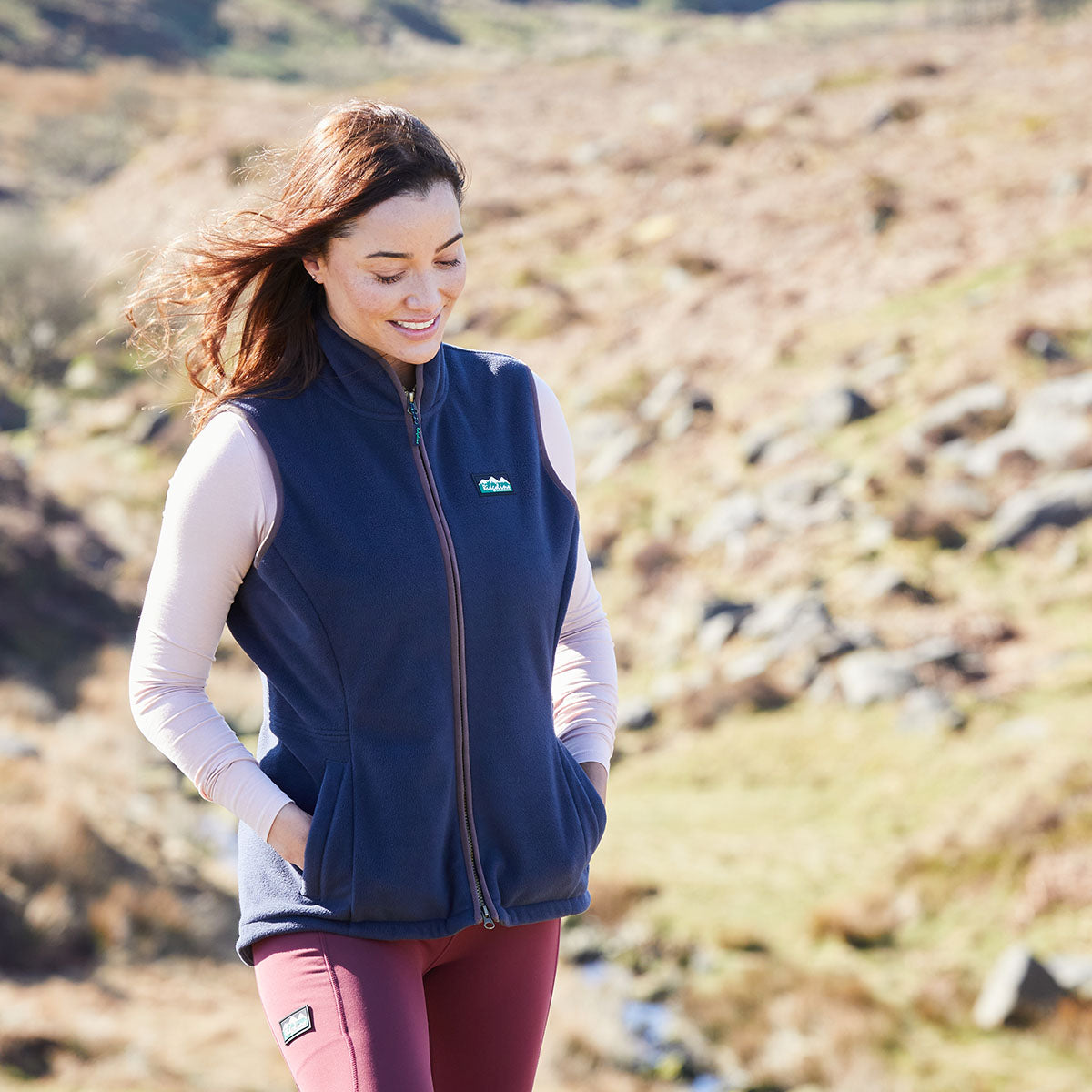 Woman wearing a navy blue vest with a Ridgeline Clothing logo in a natural setting