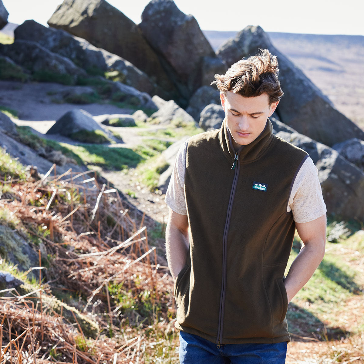 Person wearing a brown vest with a Ridgeline Clothing logo in a natural setting