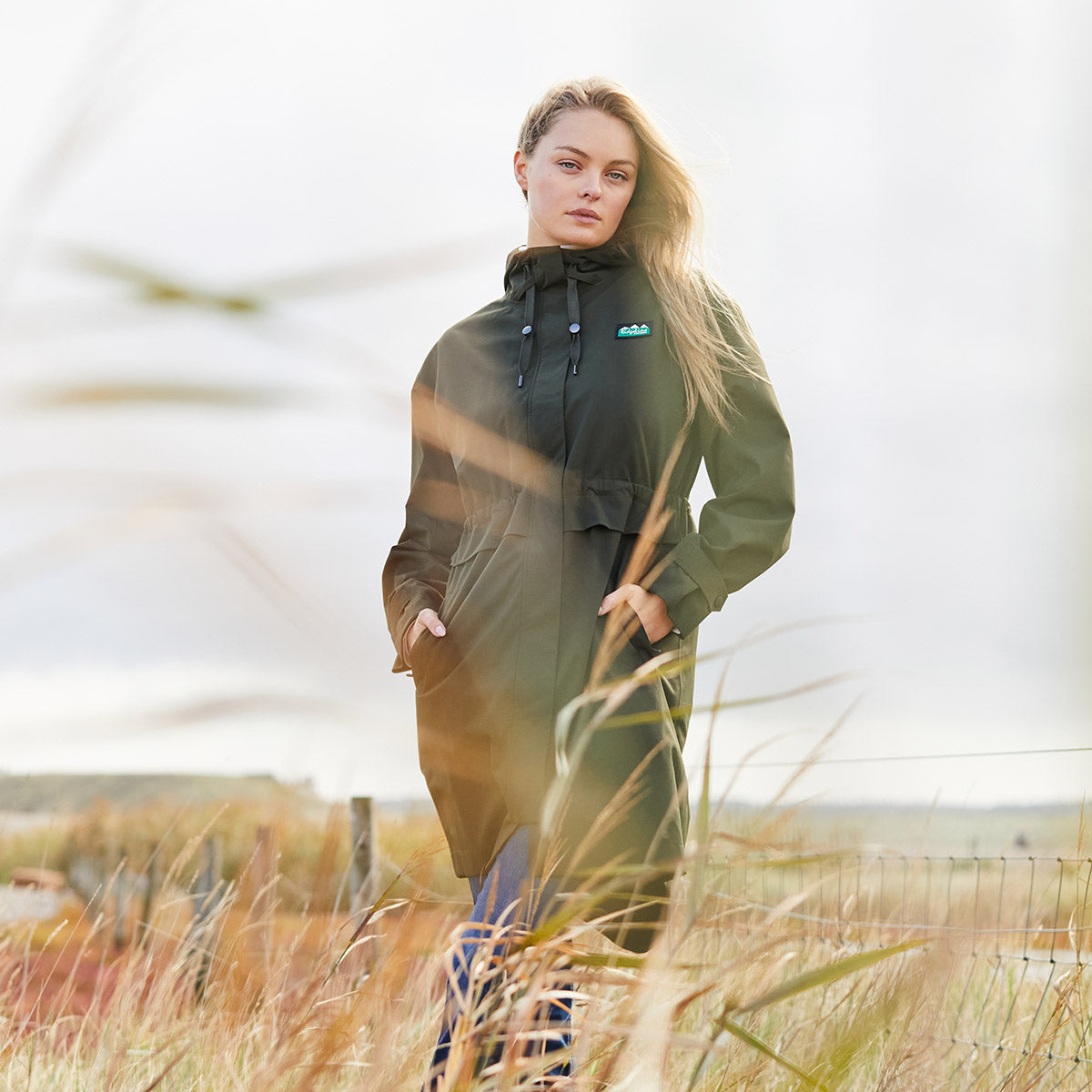 Woman wearing a green raincoat in the middle of field