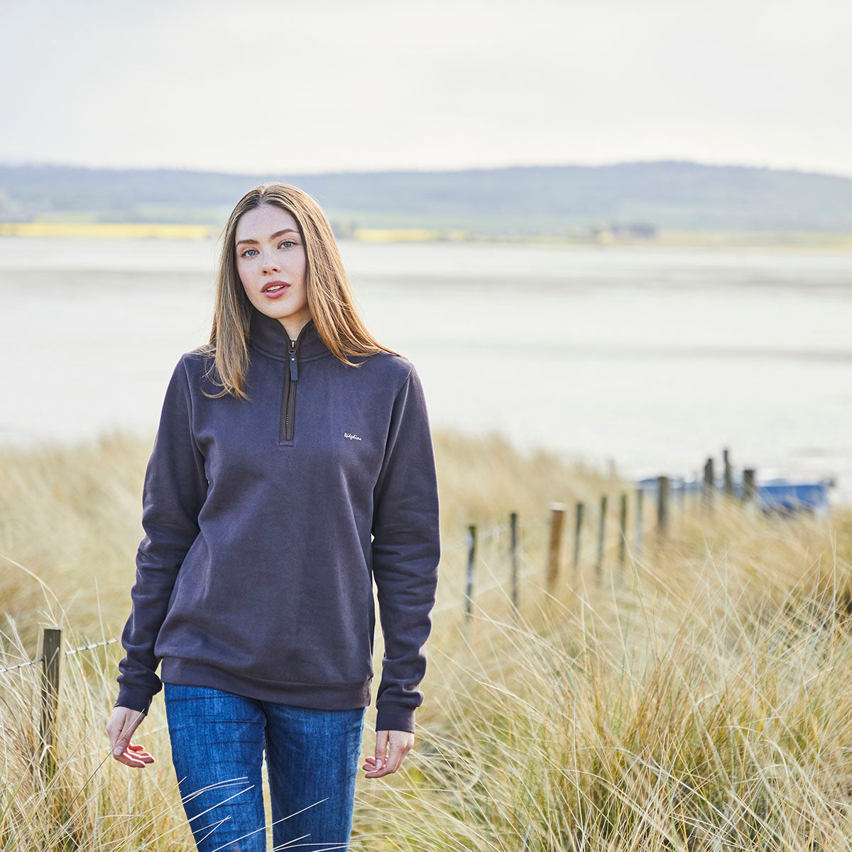 Dark charcoal half zip fleece pullover, outdoor view, worn with blue jeans