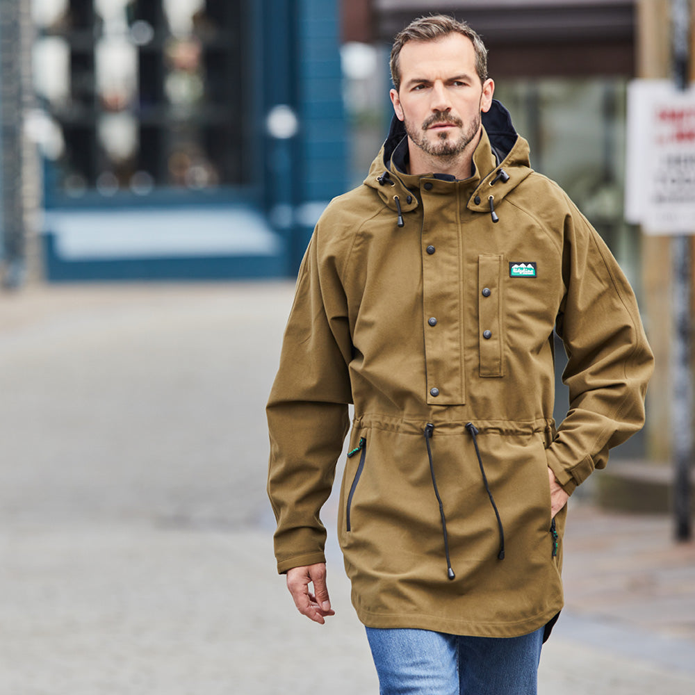 A brown Ridgeline smock with a hood, chest pocket, and lower zip pockets worn by a man in the streets.