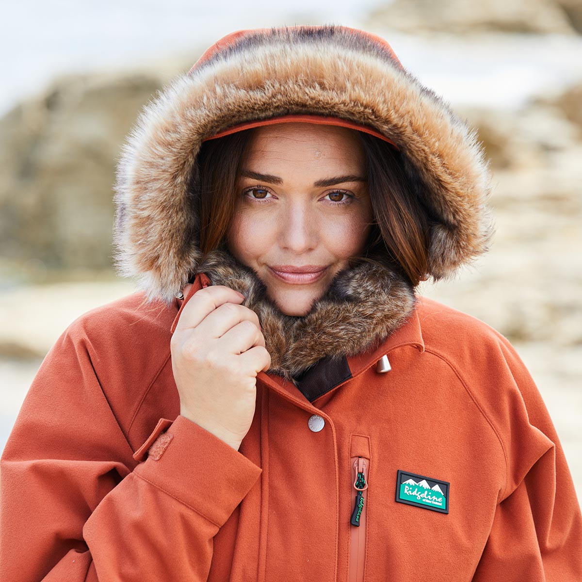 Person wearing an orange jacket with a fur-lined hood outdoors