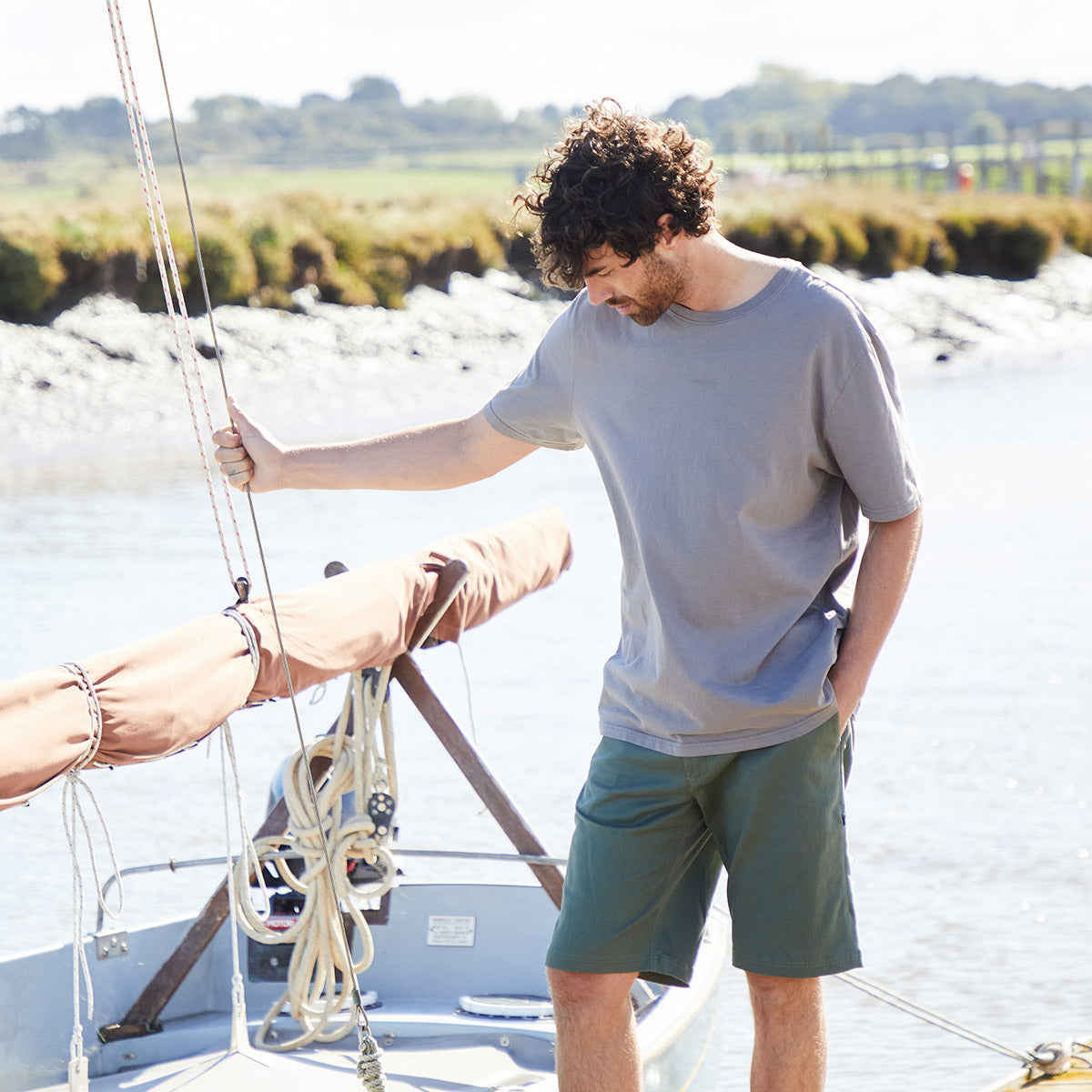 Man wearing Green Chino Shorts while holding onto sail on a boat