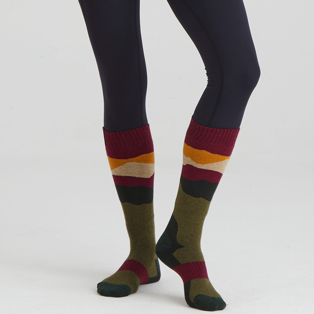Colorful striped socks worn with black leggings on a white background