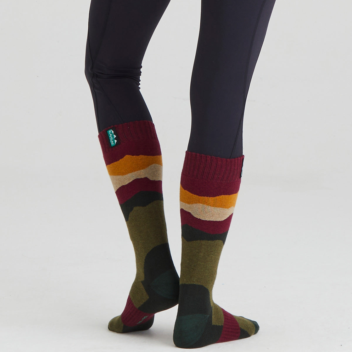 Colorful striped socks worn with dark leggings on a white background