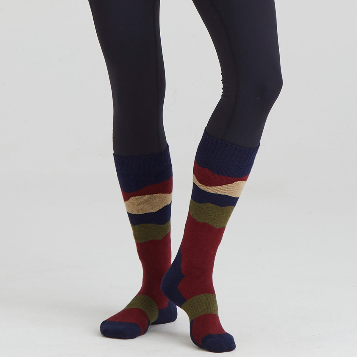Colorful striped socks worn with black leggings on a white background