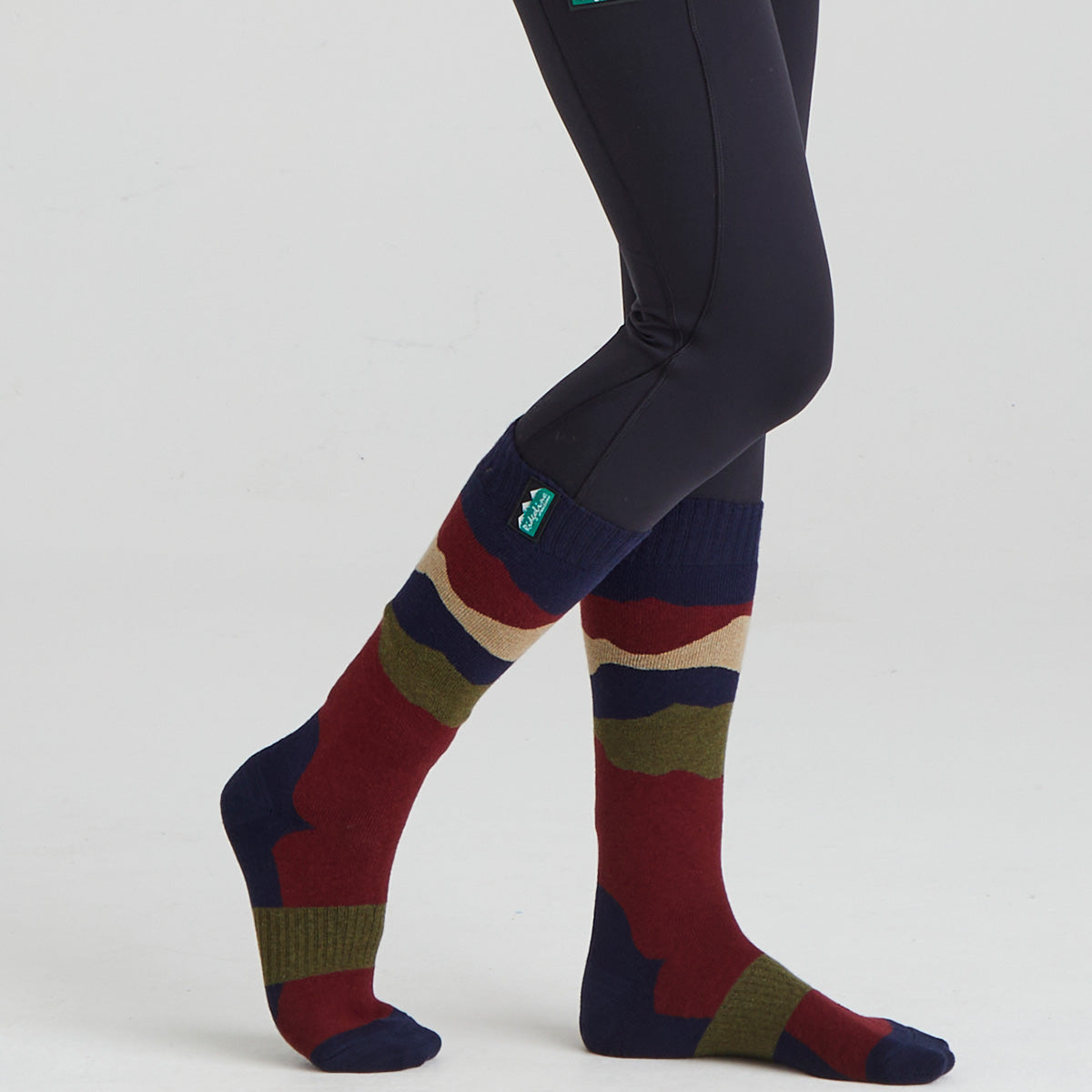 Colorful striped socks worn with dark leggings on a light grey background
