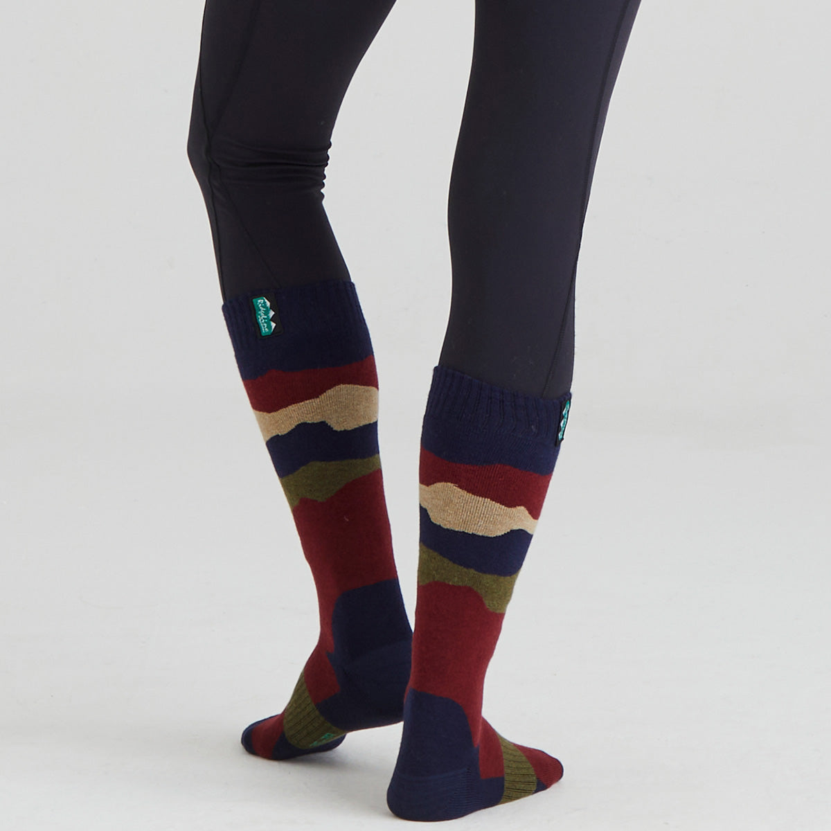 Colorful knee-high socks with a pattern worn with black leggings on a white background
