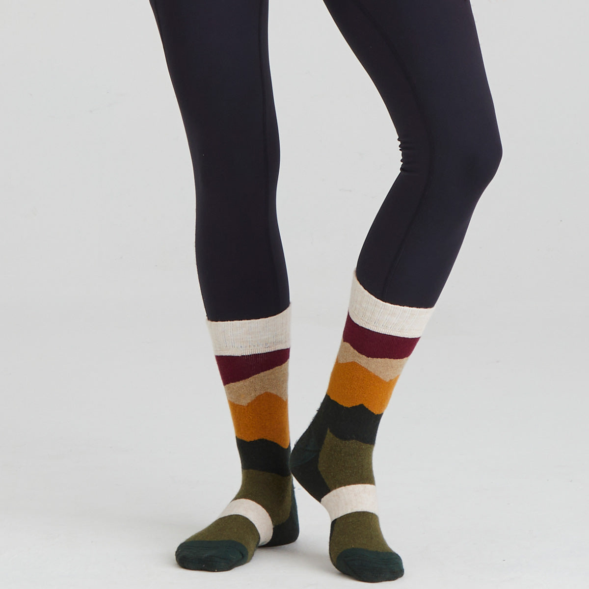 Colourful striped socks worn with dark leggings on a light grey background
