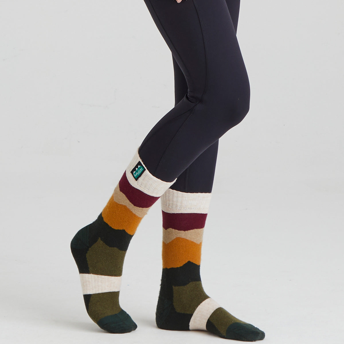 Colourful striped socks worn with dark leggings on a white background