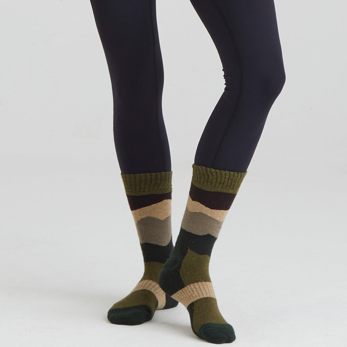 Striped socks worn with dark leggings on a white background