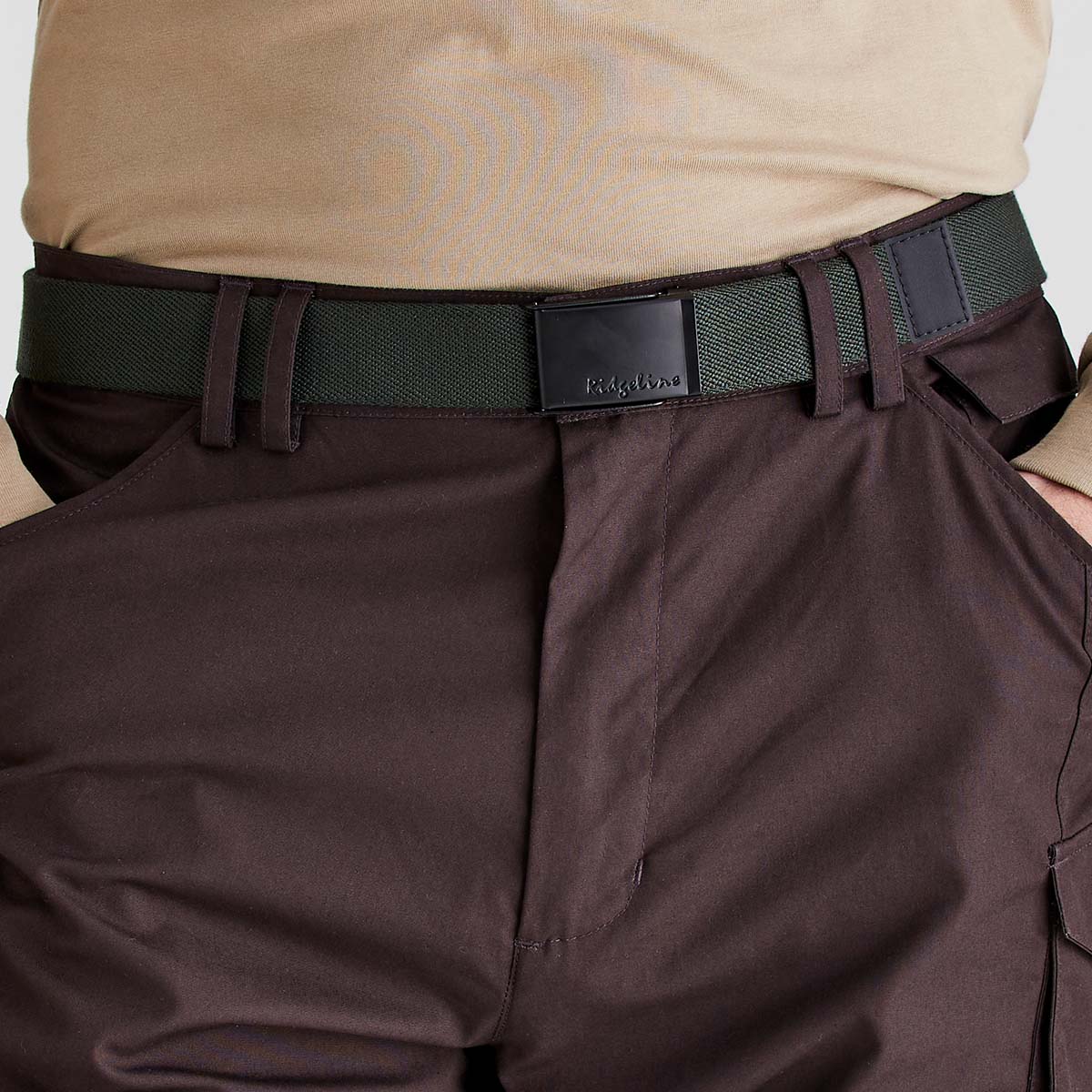 Ridgeline green woven fabric belt with black plaque buckle, worn with trousers, front close-up