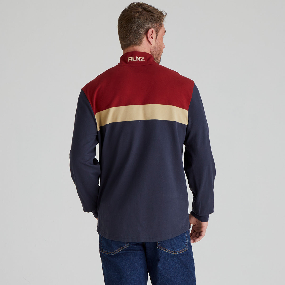 Man wearing a multi-coloured shirt with 'RLNZ' branding on the back, standing against a plain background.