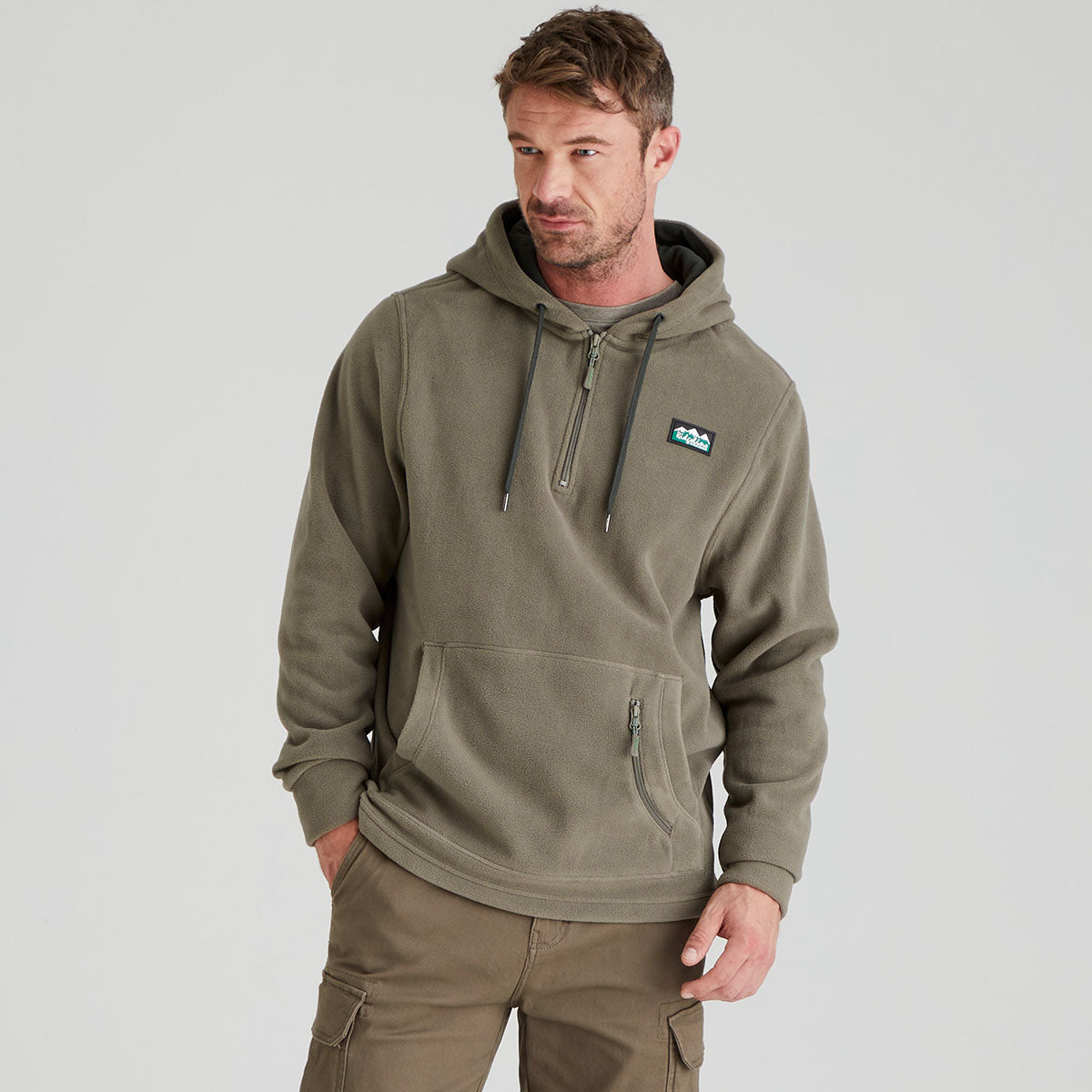 Man wearing a green fleece hoodie with a logo on a grey background