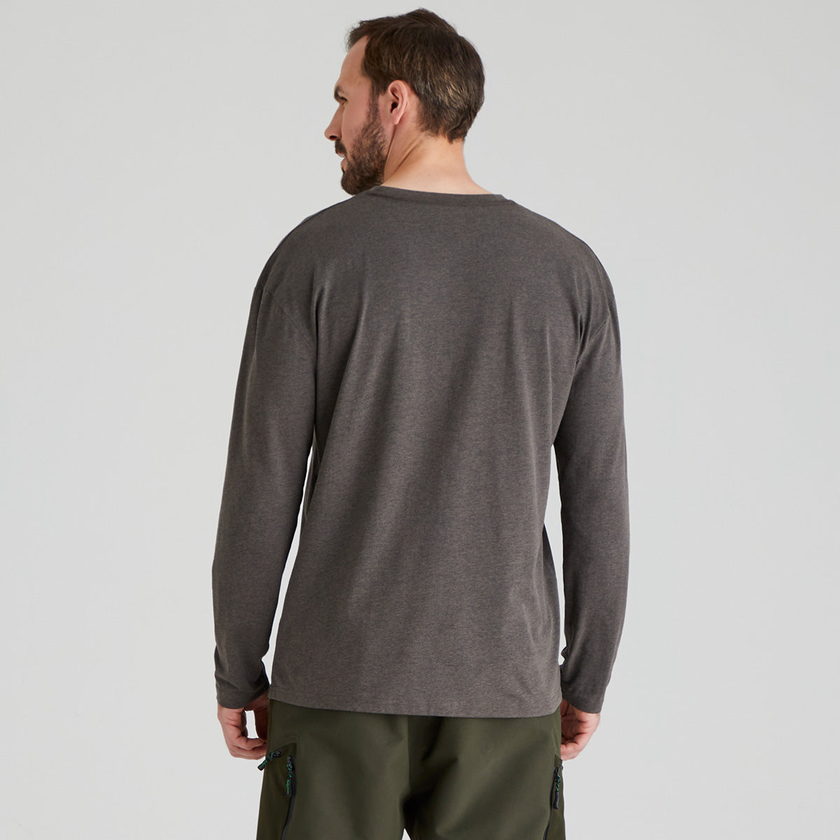 back view of man wearing a grey long-sleeve shirt and green pants on a light grey background