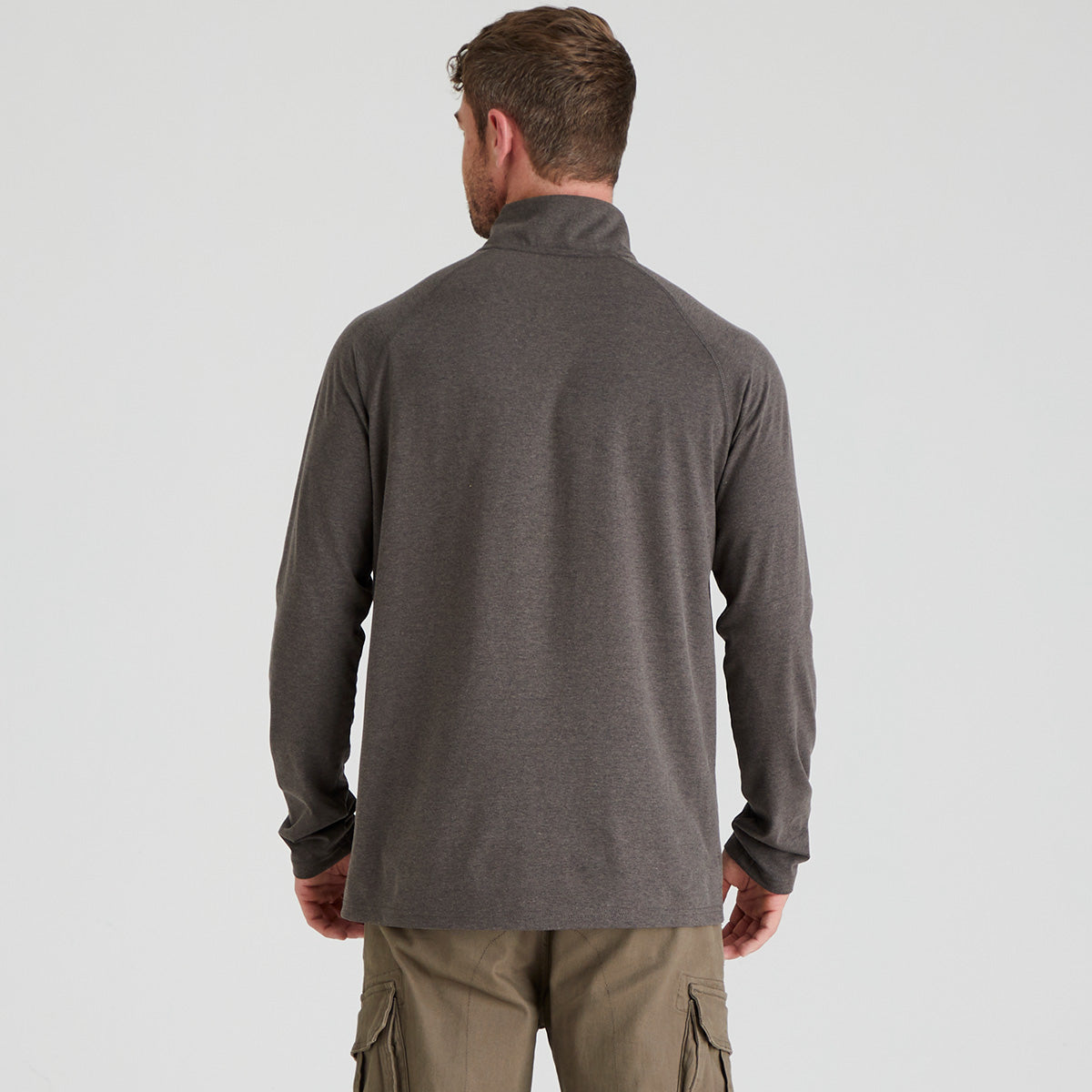 Man wearing a gray long-sleeve shirt and beige cargo pants on a light gray background