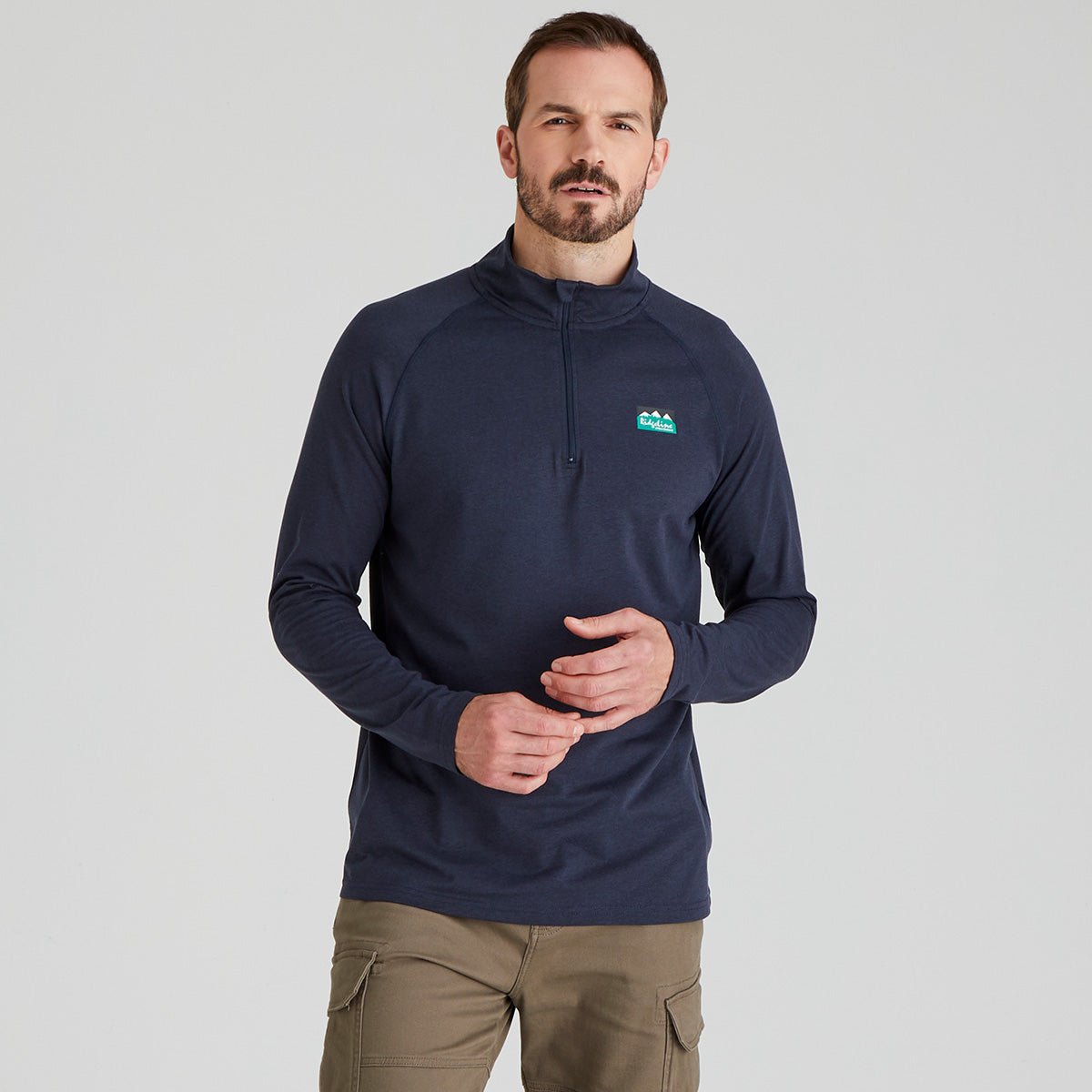Man wearing a navy blue pullover with a logo on a gray background