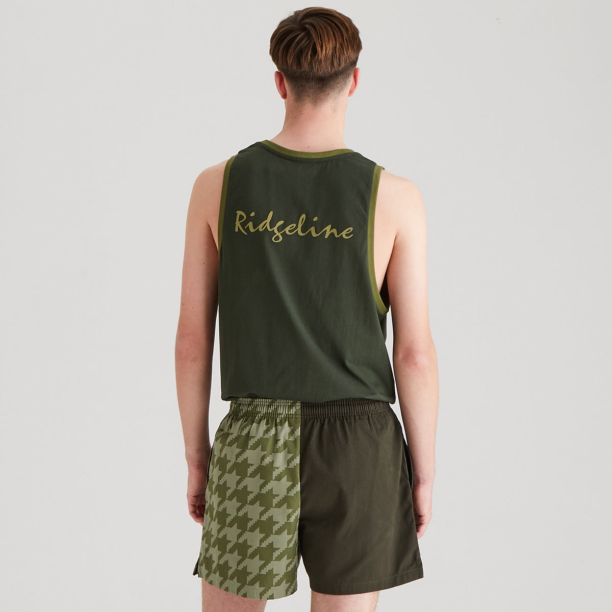 Person wearing a green tank top and shorts with 'Ridgeline' branding on a light gray background