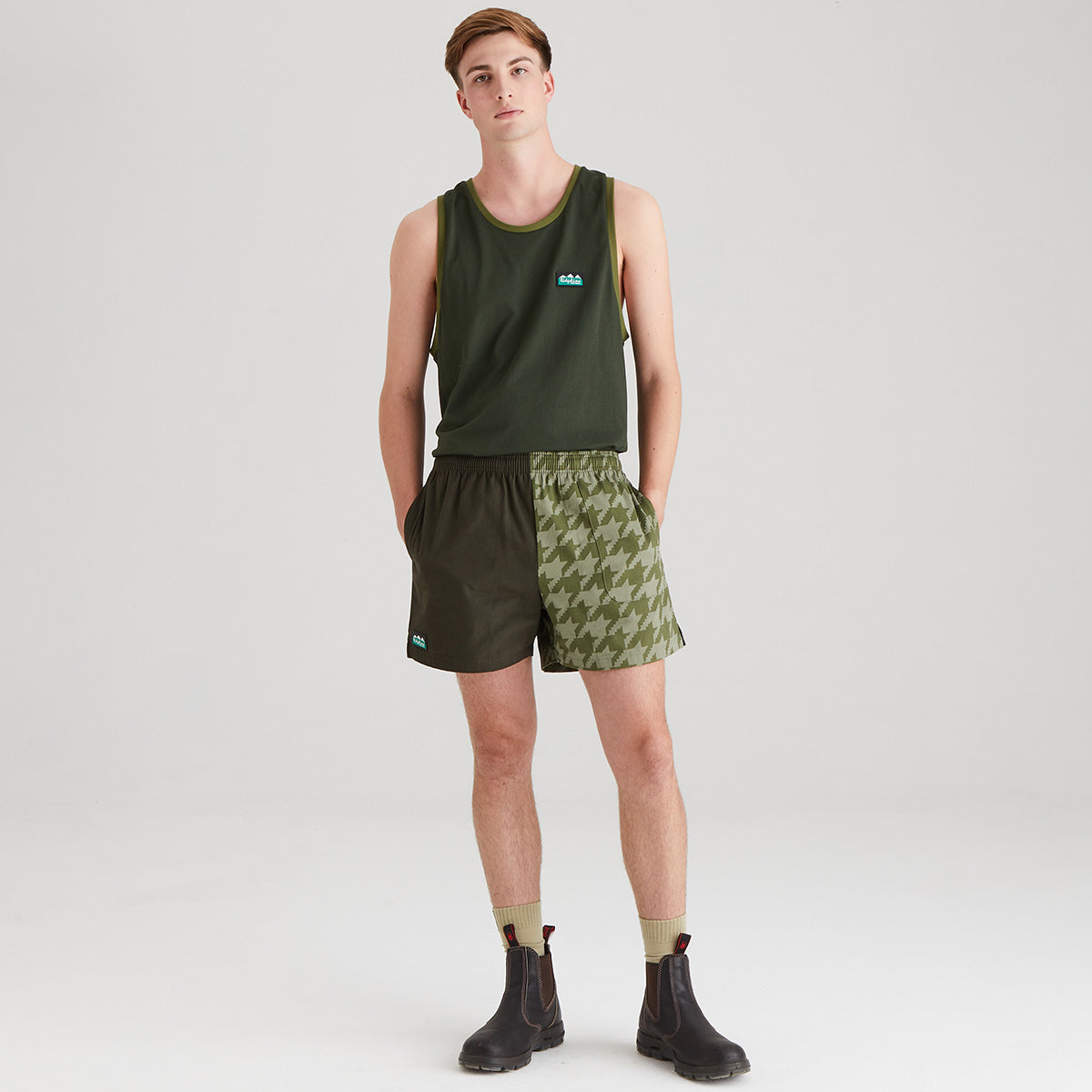 Person wearing a green tank top and patterned shorts on a white background