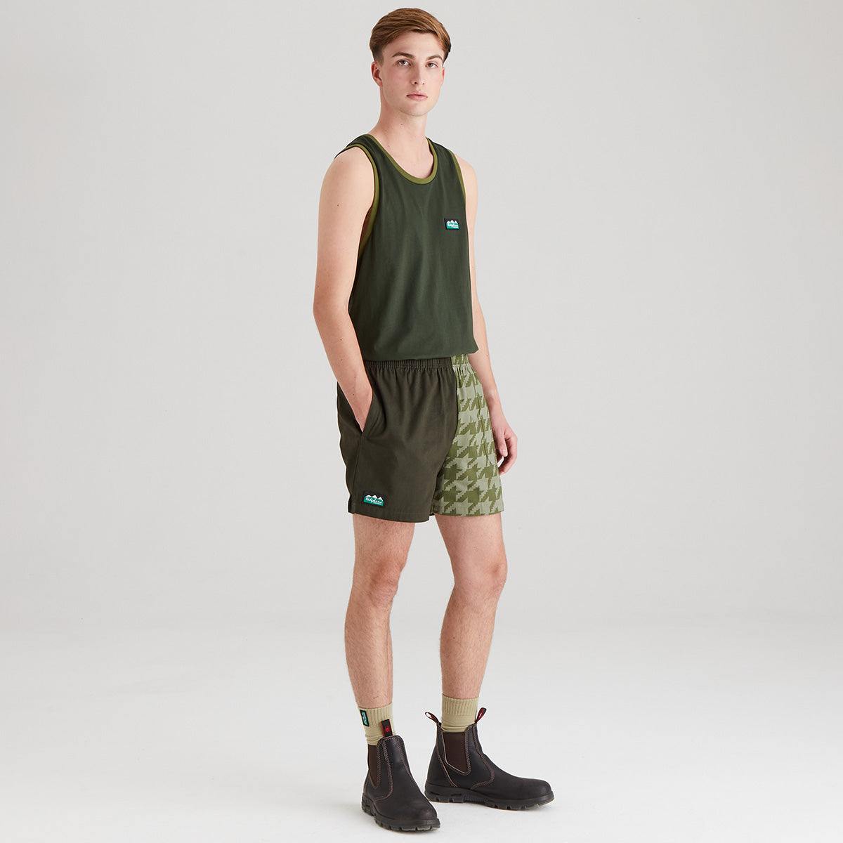 Person wearing a green tank top and shorts with camouflage pattern on a white background
