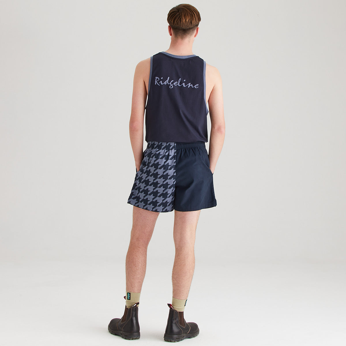 Person wearing a navy tank top and shorts with houndstooth pattern on a plain background
