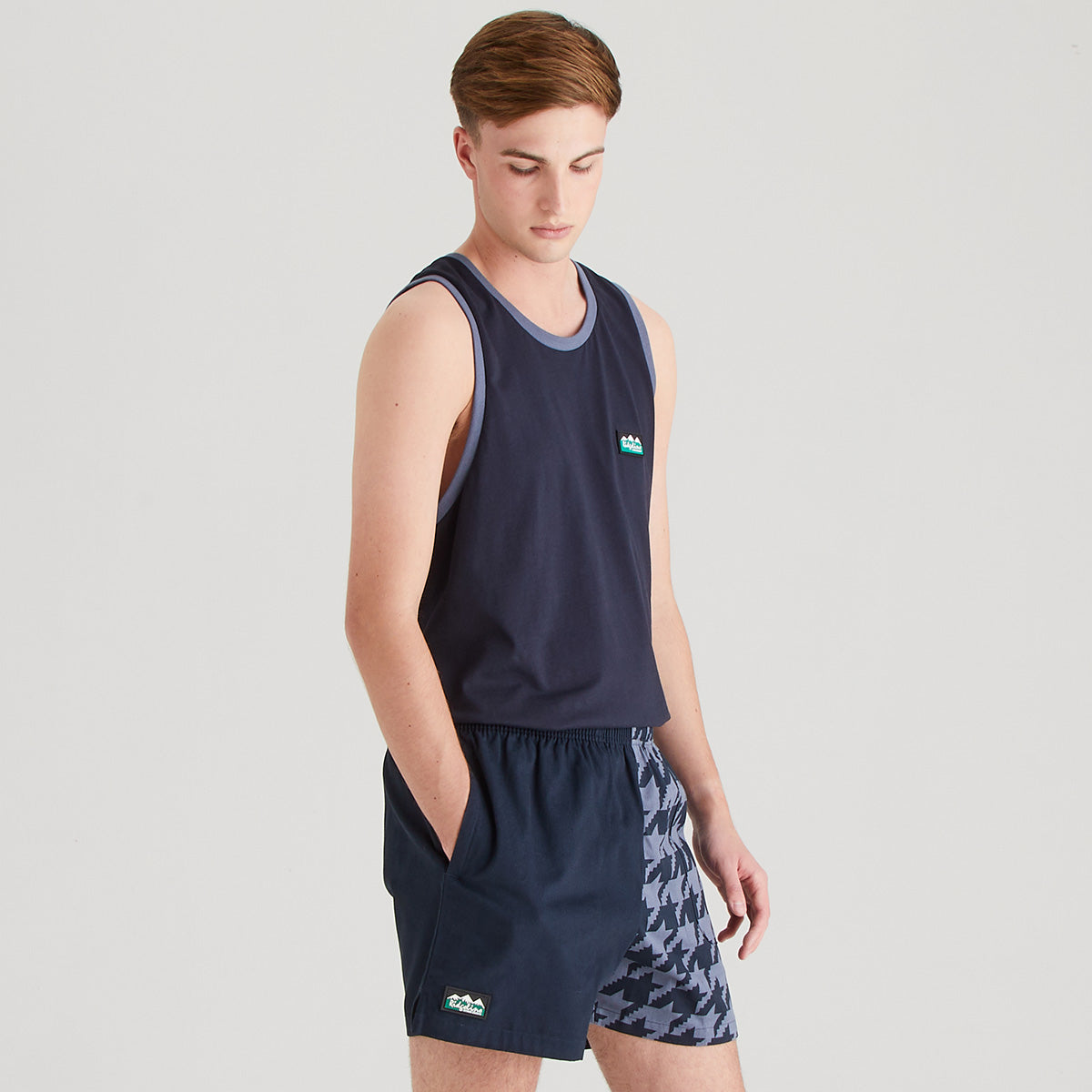 Person wearing a navy tank top and shorts with a patterned design on a light gray background