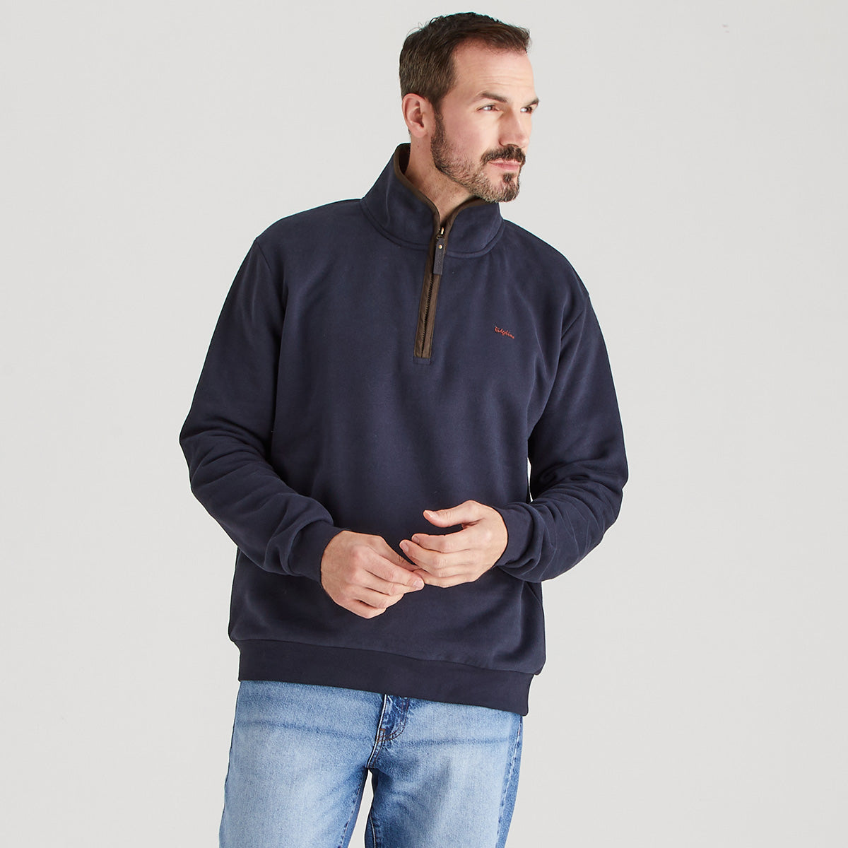 Man wearing a navy blue pullover with a small logo on a light gray background