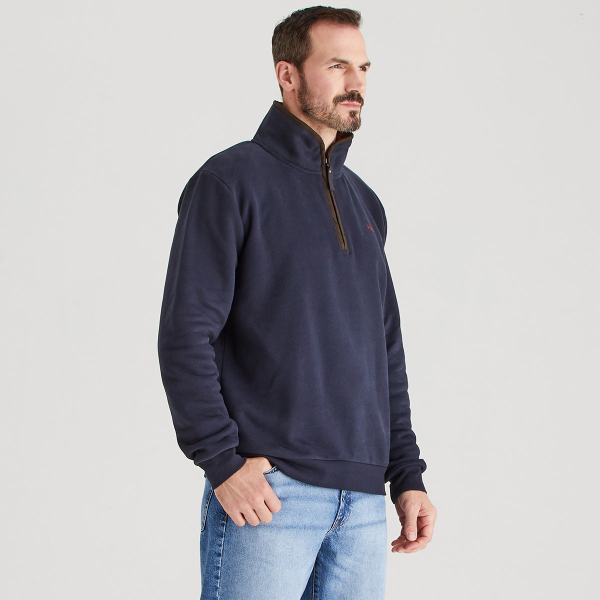 Man wearing a navy blue pullover with a zipper on a light gray background