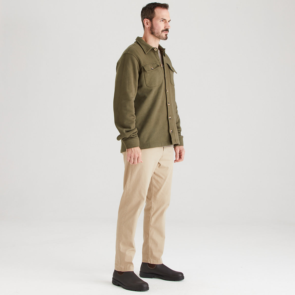 Man wearing a green shirt and beige pants on a white background