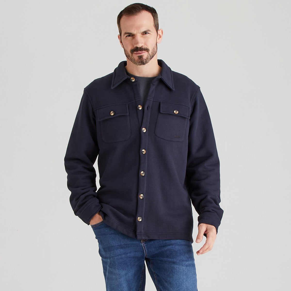 Man wearing a navy blue shacket on a gray background