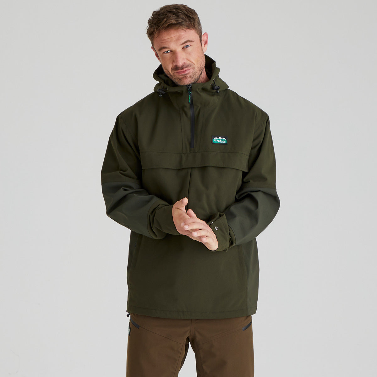 Olive green hooded overhead jacket with half zip front and chest logo, model view