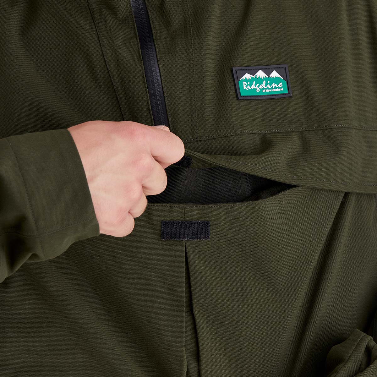 Close-up of a green jacket front chest/ belly pocket with a Ridgeline Clothing brand logo on the chest pocket.
