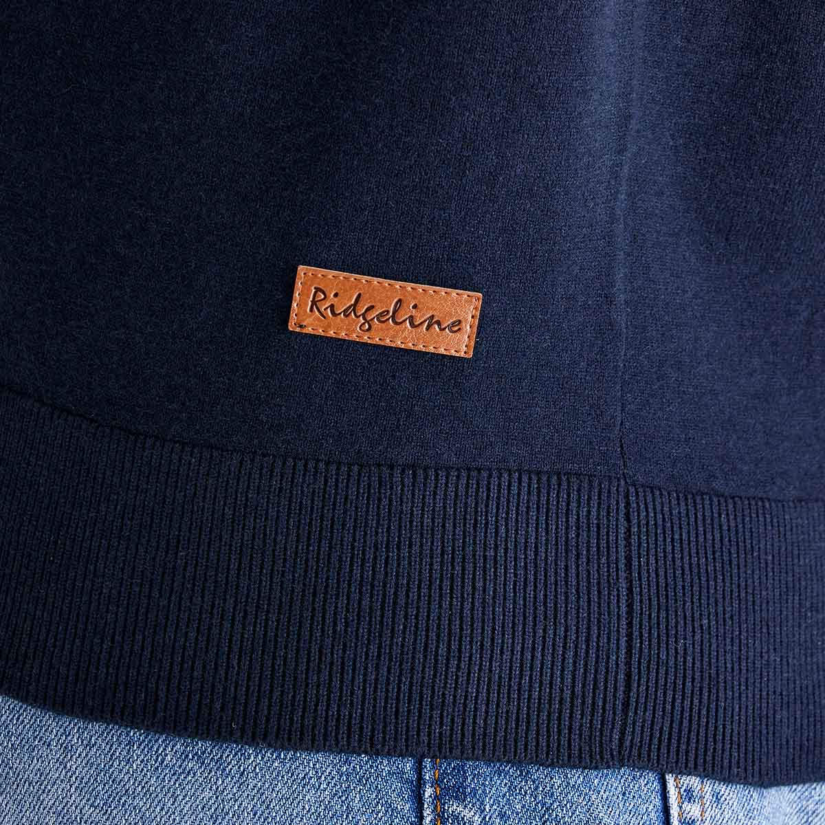 Navy blue jacket with a brown leather label on a blue jeans background