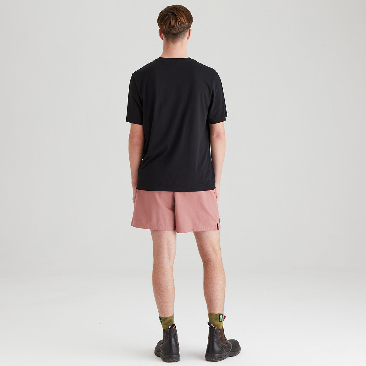 Person wearing a black t-shirt and pink shorts on a plain background