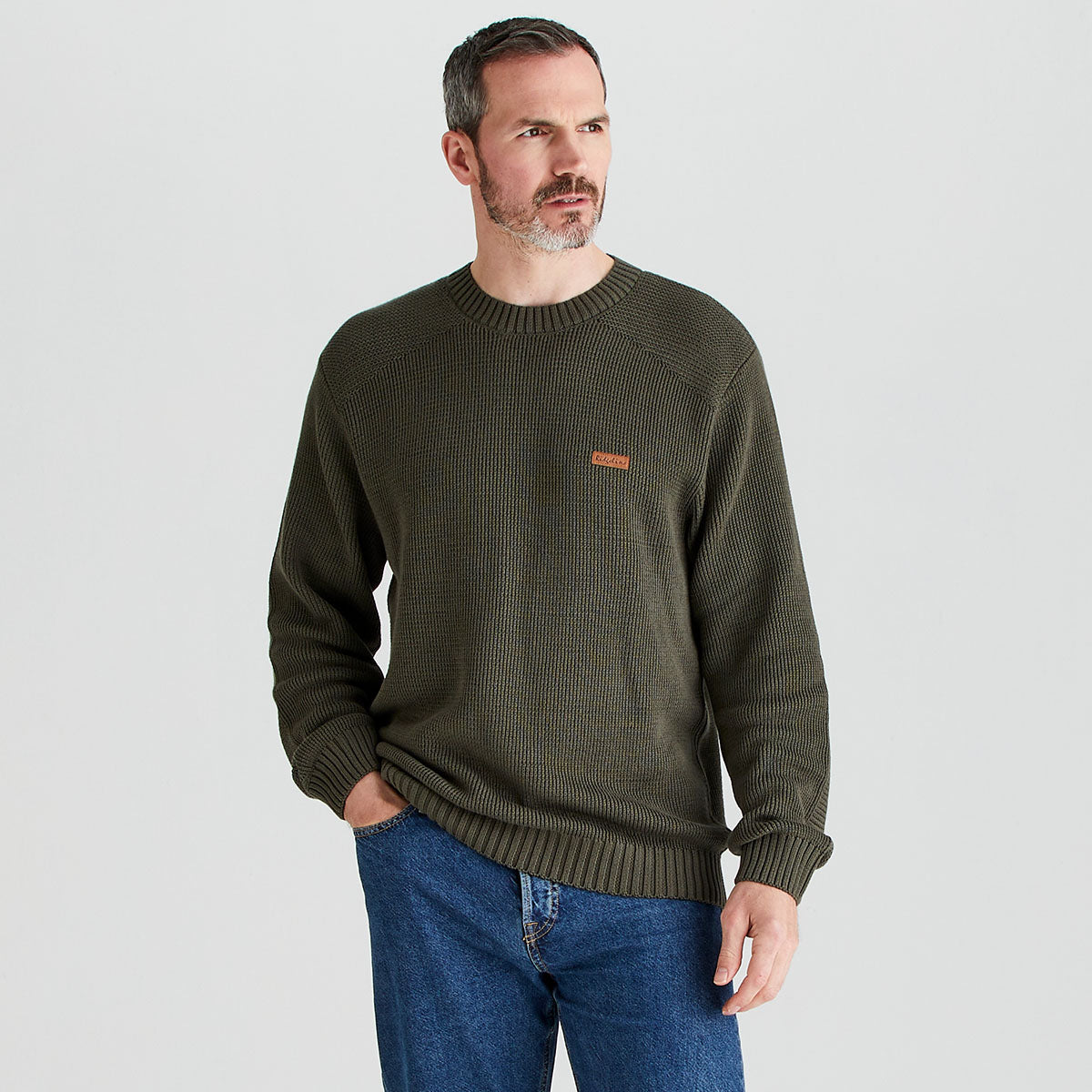 Man wearing a green sweater with a small logo on a light gray background