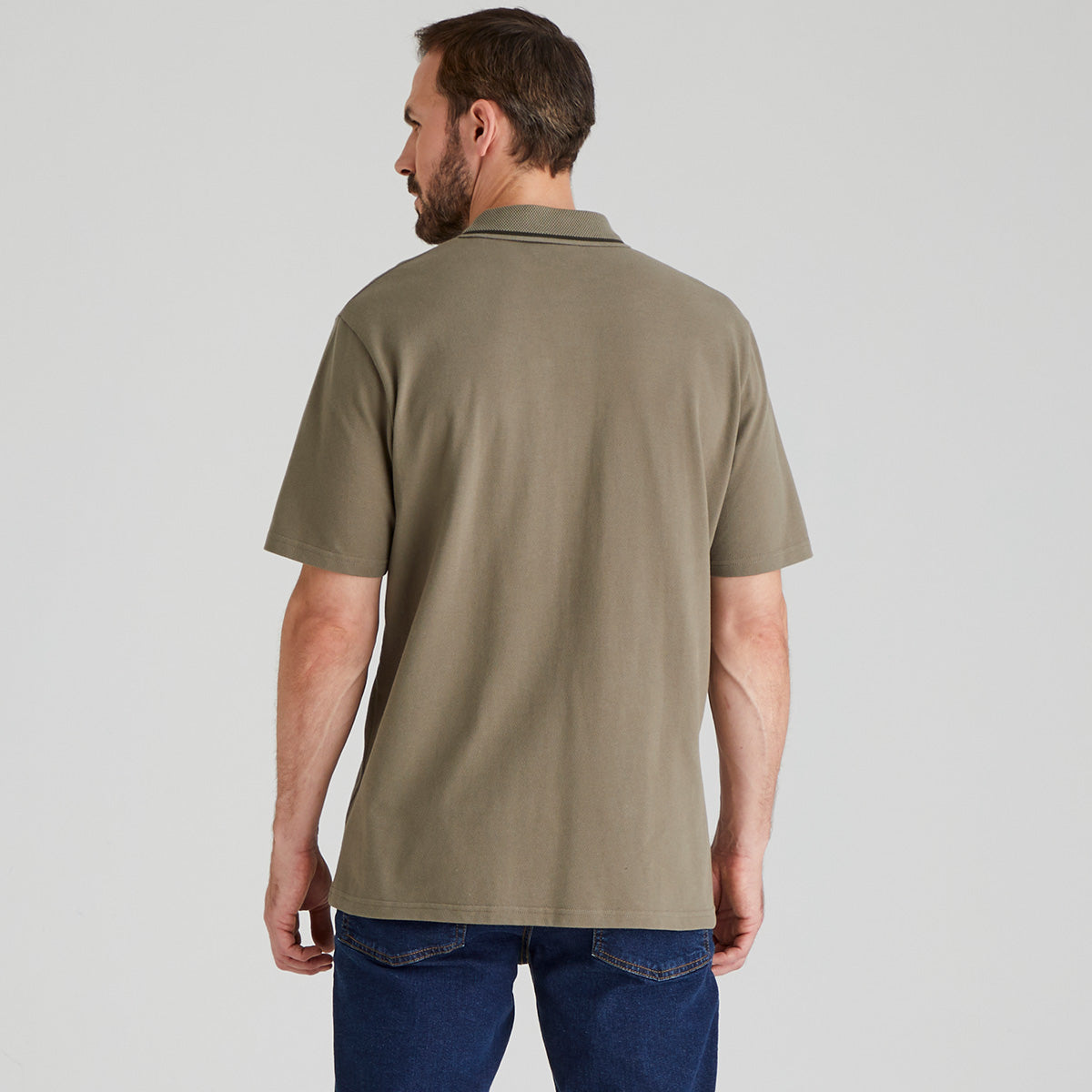 back view of man wearing a Olive polo shirt on a plain background