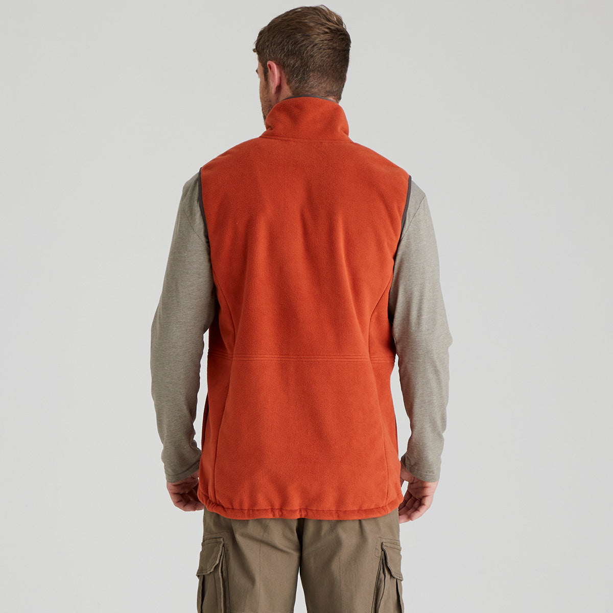back view of person wearing an orange vest over a grey shirt on a light grey background