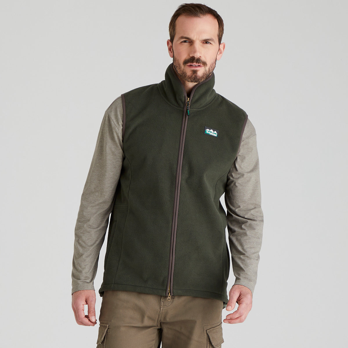 Man wearing a green fleece gilet with a visible ridgeline clothing brand logo on a light grey background