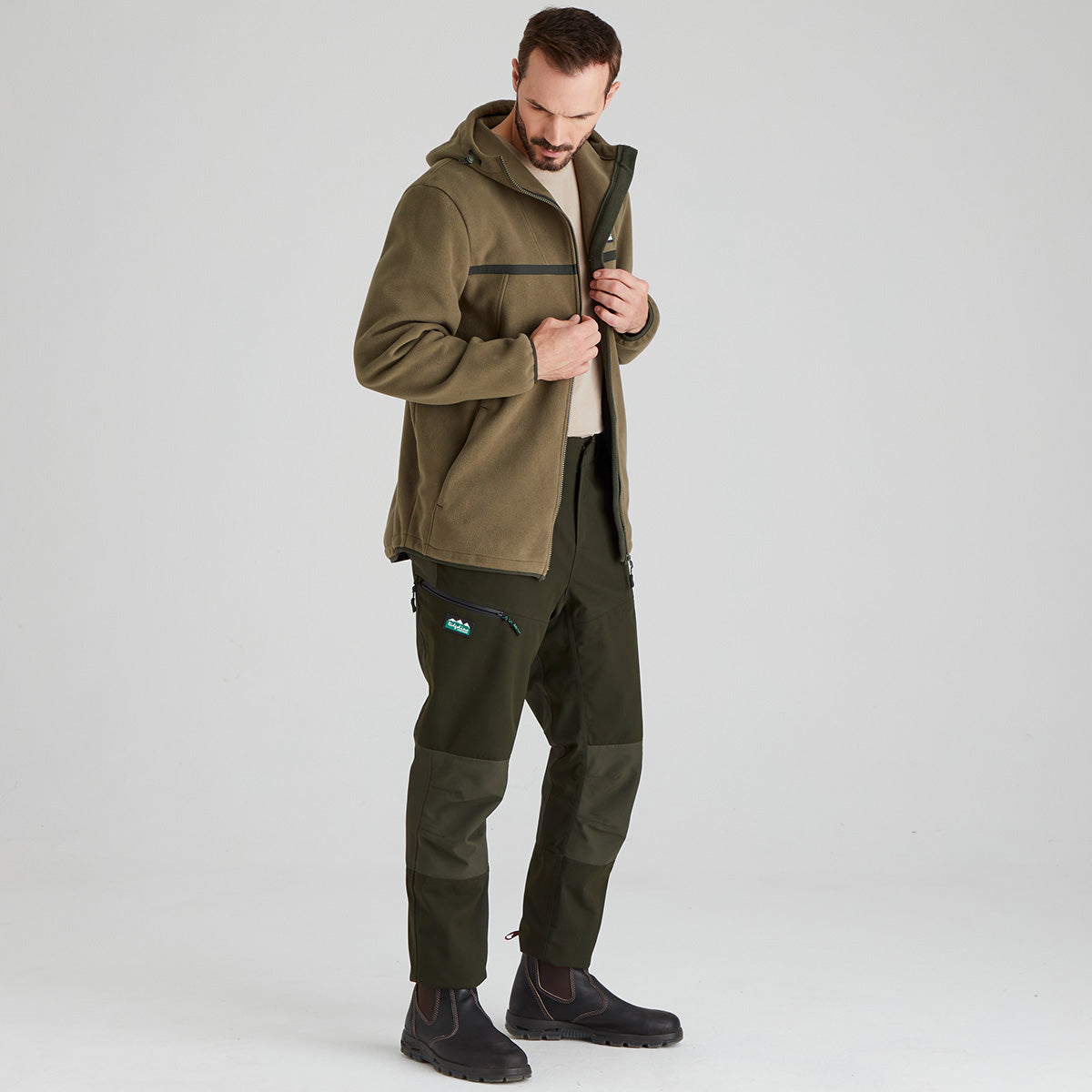 Man wearing a green windproof jacket and pants on a white background