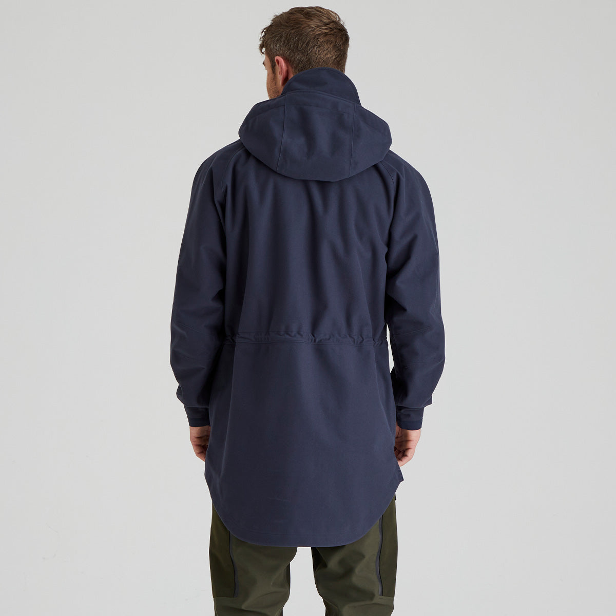 back view of man wearing a navy blue hooded coat on a light grey background