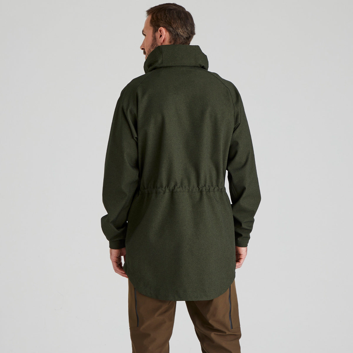 Back view of man wearing a green jacket on a light grey background