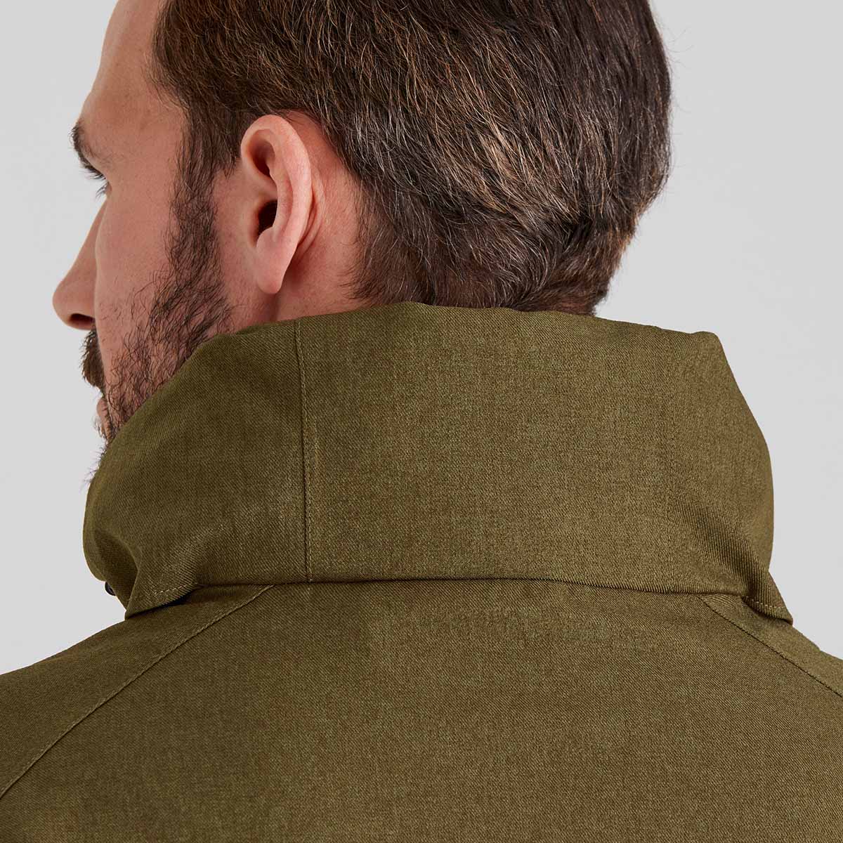 Close-up of a person wearing a green jacket on a plain background