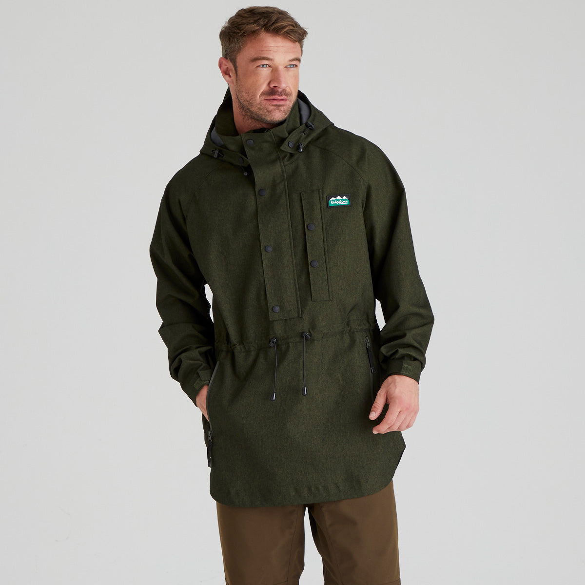 Man wearing a green waterproof smock with a ridgeline clothing brand logo on a grey background
