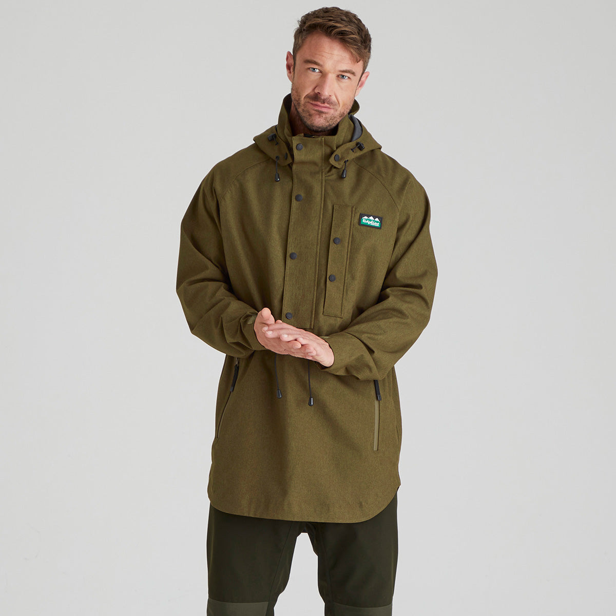 Man wearing a green jacket with a brand logo on a grey background