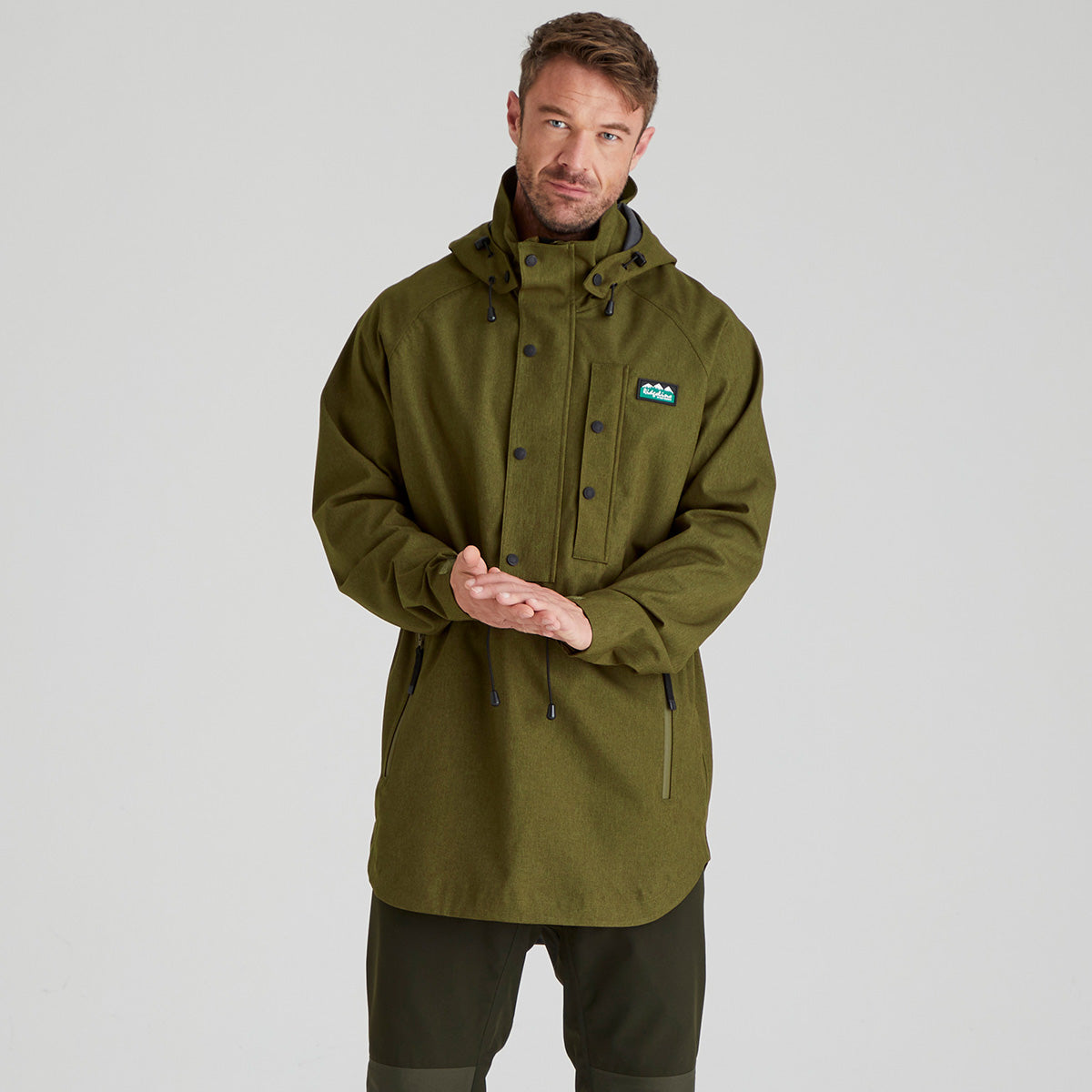 Man wearing a brown jacket with a brand logo on a grey background