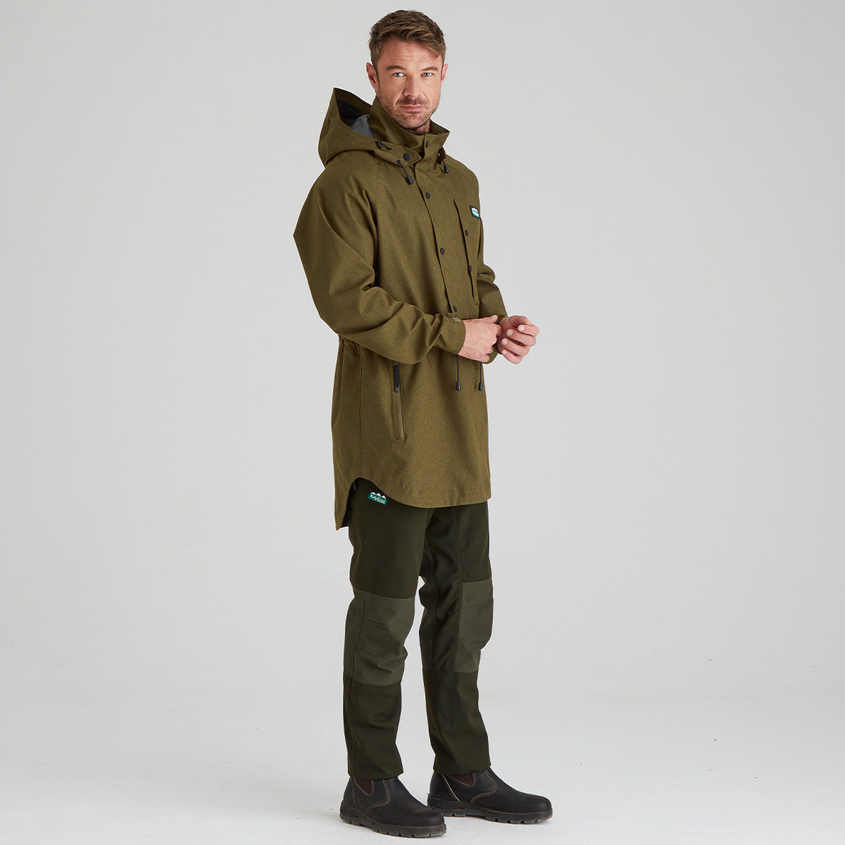 Man wearing a green raincoat and pants on a white background