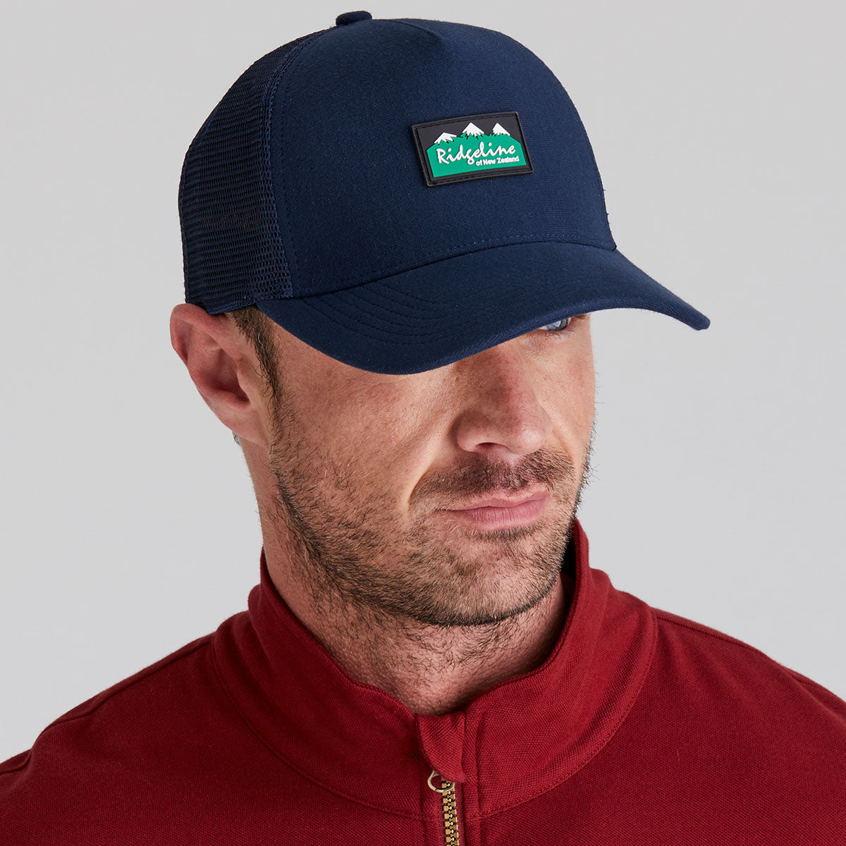 Man wearing a navy blue cap with a ridgeline clothing logo on a grey background