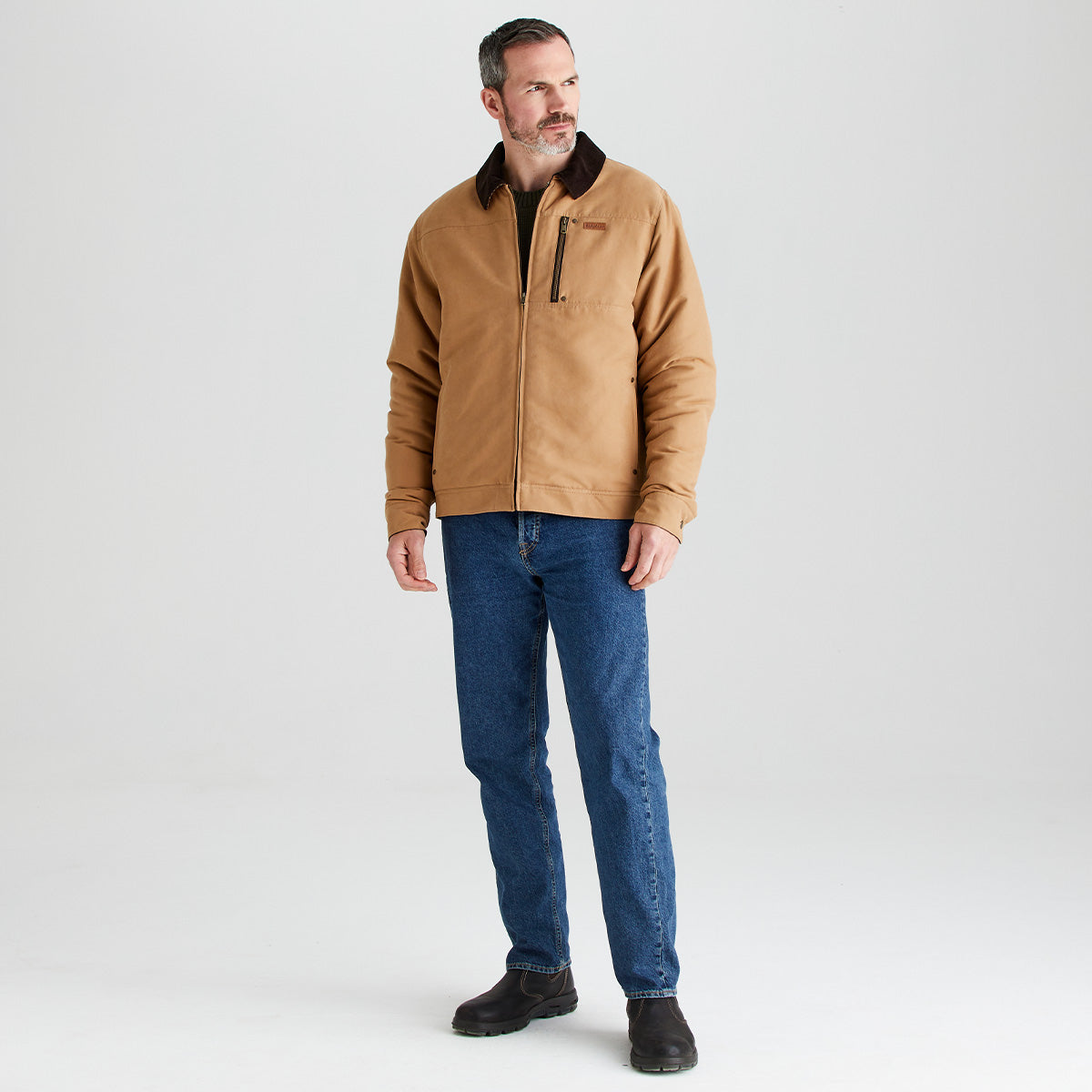 Man wearing a brown jacket and blue jeans on a white background