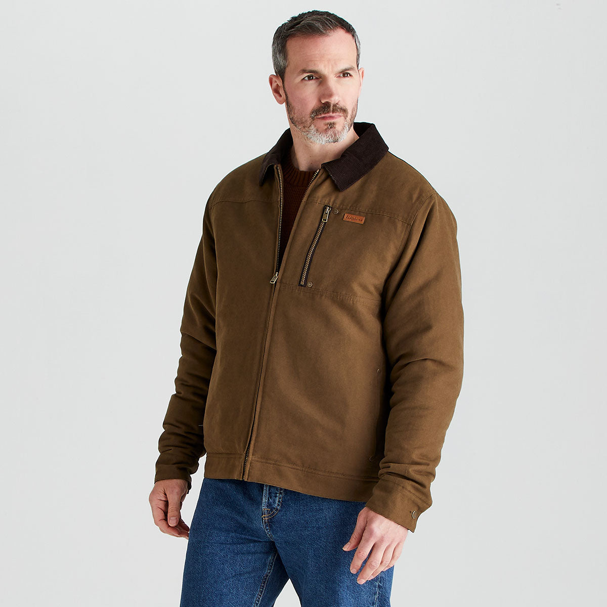 Man wearing a brown jacket with a visible brand logo on a light gray background